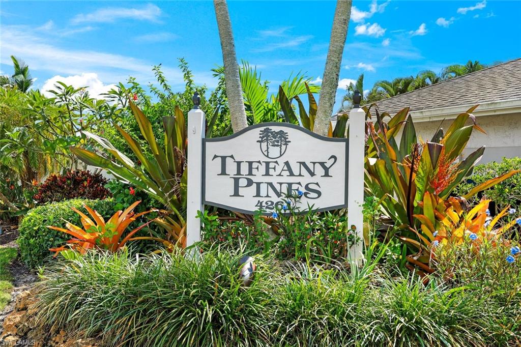 Tiffany Pines entrance sign amid tropical landscaping and palm trees.