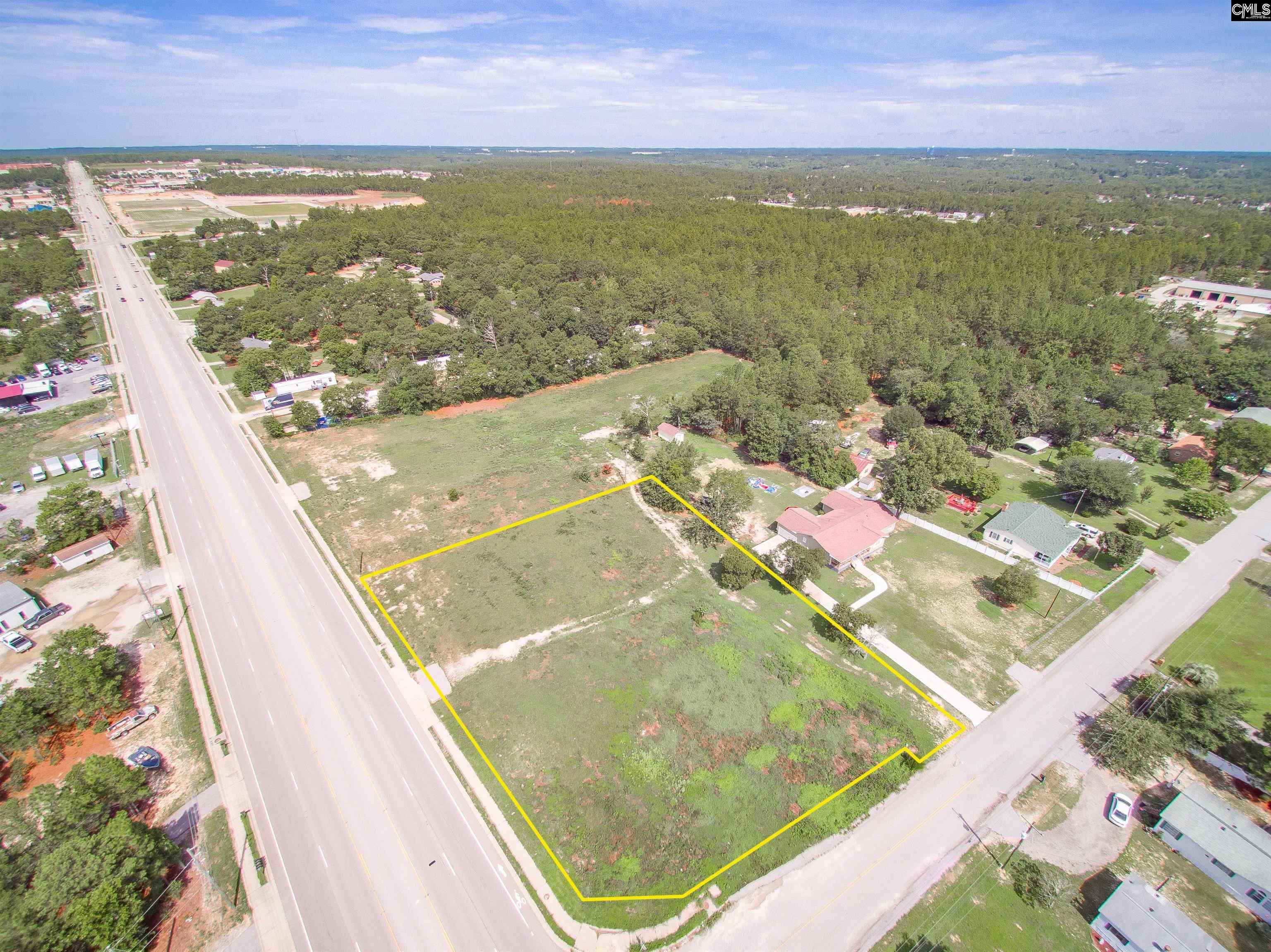 Aerial view of a vacant corner lot outlined in yellow beside two roads.
