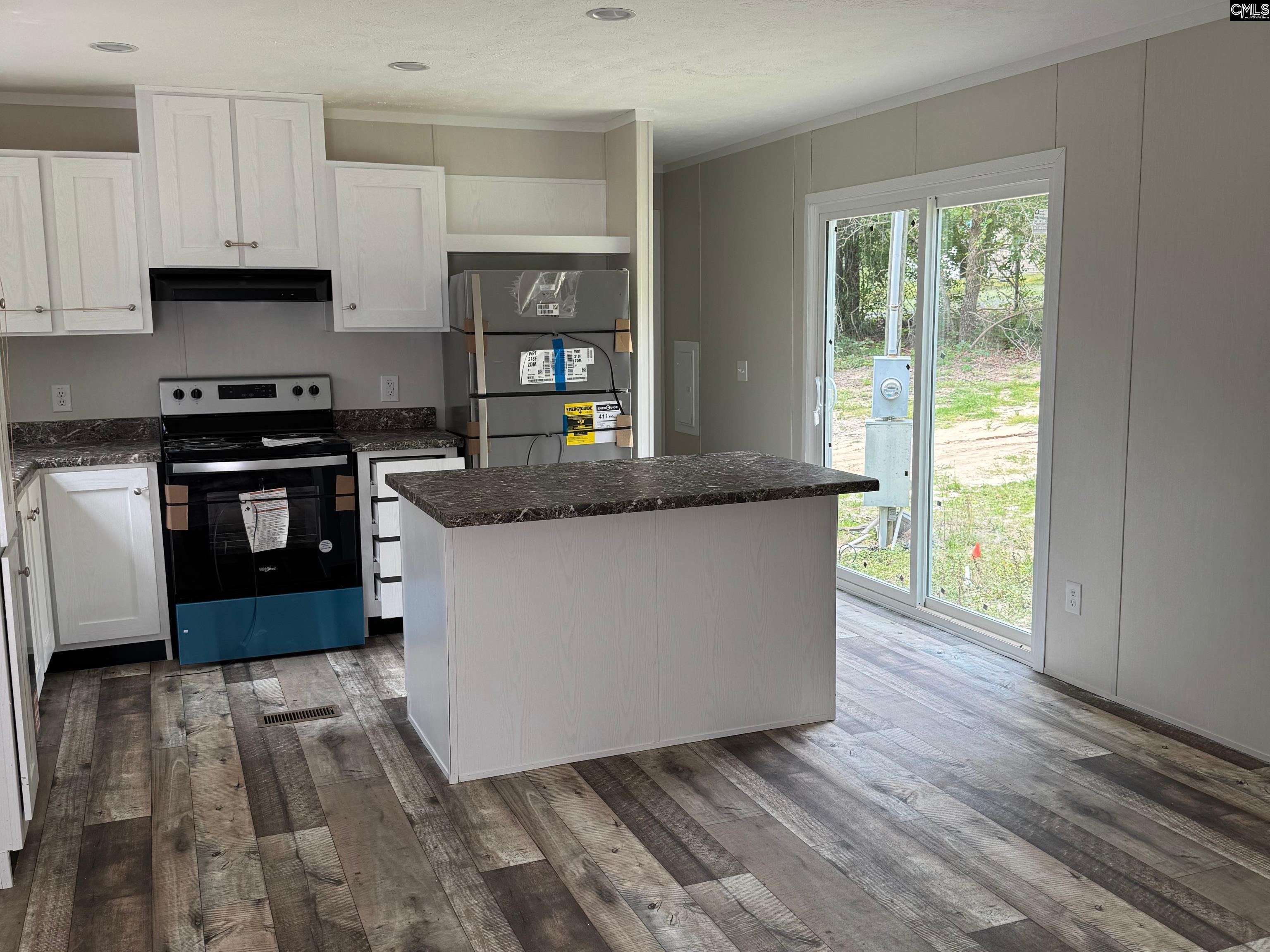 Kitchen with white cabinetry, dark countertops, a central island, and sliding glass doors to the yard.