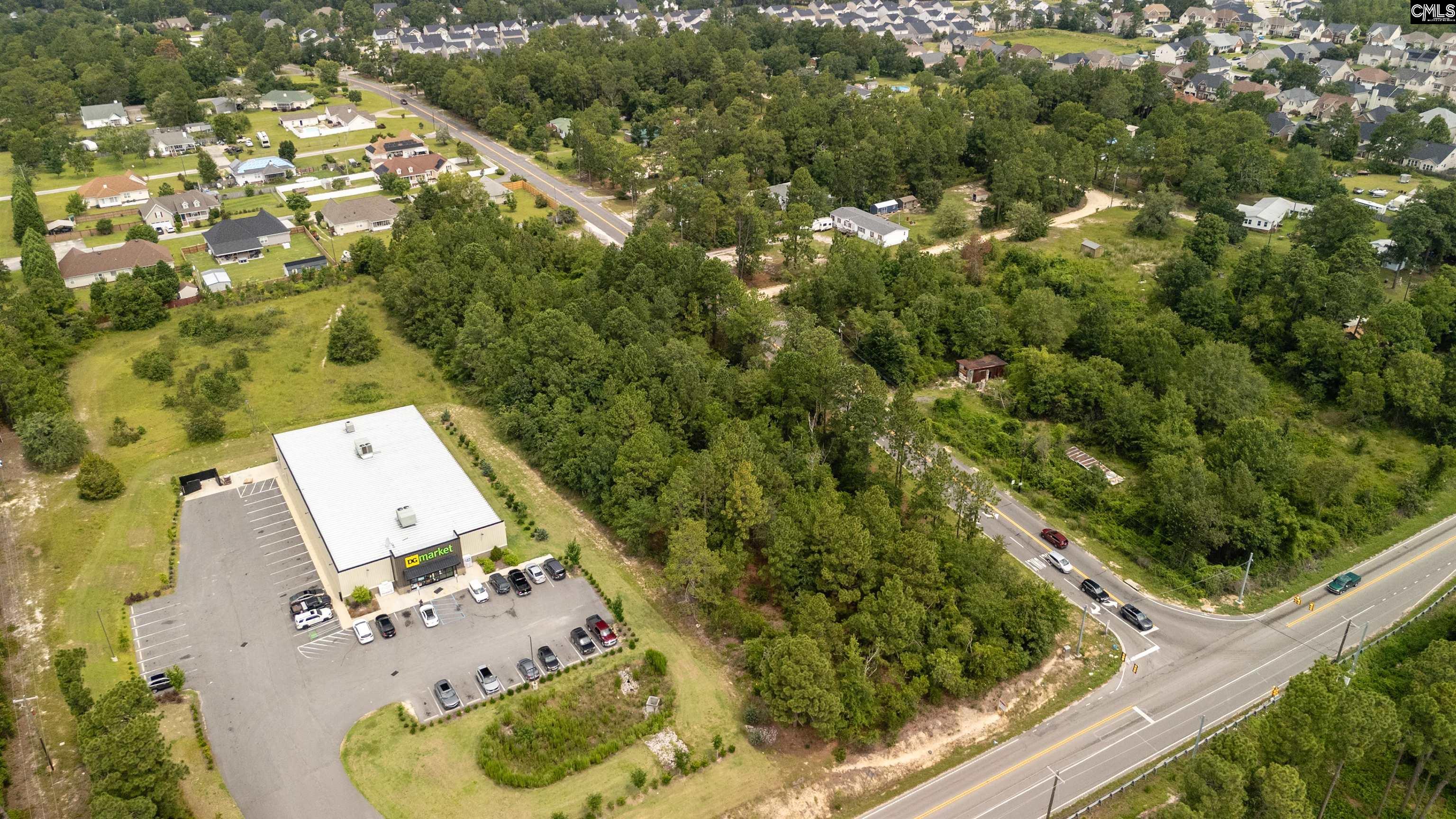 Aerial view of a DG Market and parking lot beside wooded land and a road.