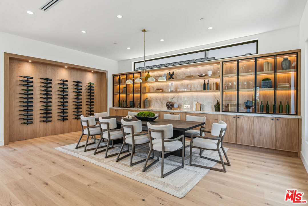 Dining room with a long table, upholstered chairs, and illuminated built-in wine storage.
