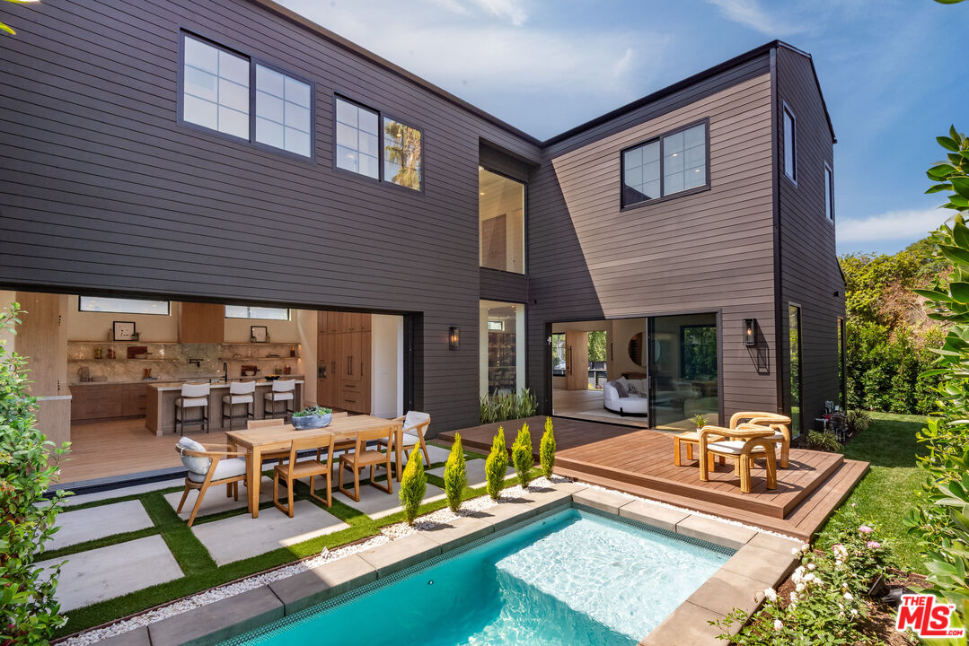 Modern two-story home's rear exterior with a swimming pool, deck, and open kitchen.