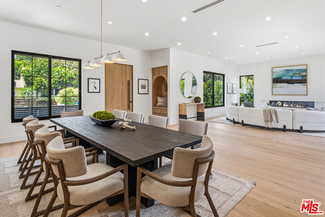 Open-plan dining and living room with a long dark table, large windows, and a fireplace.