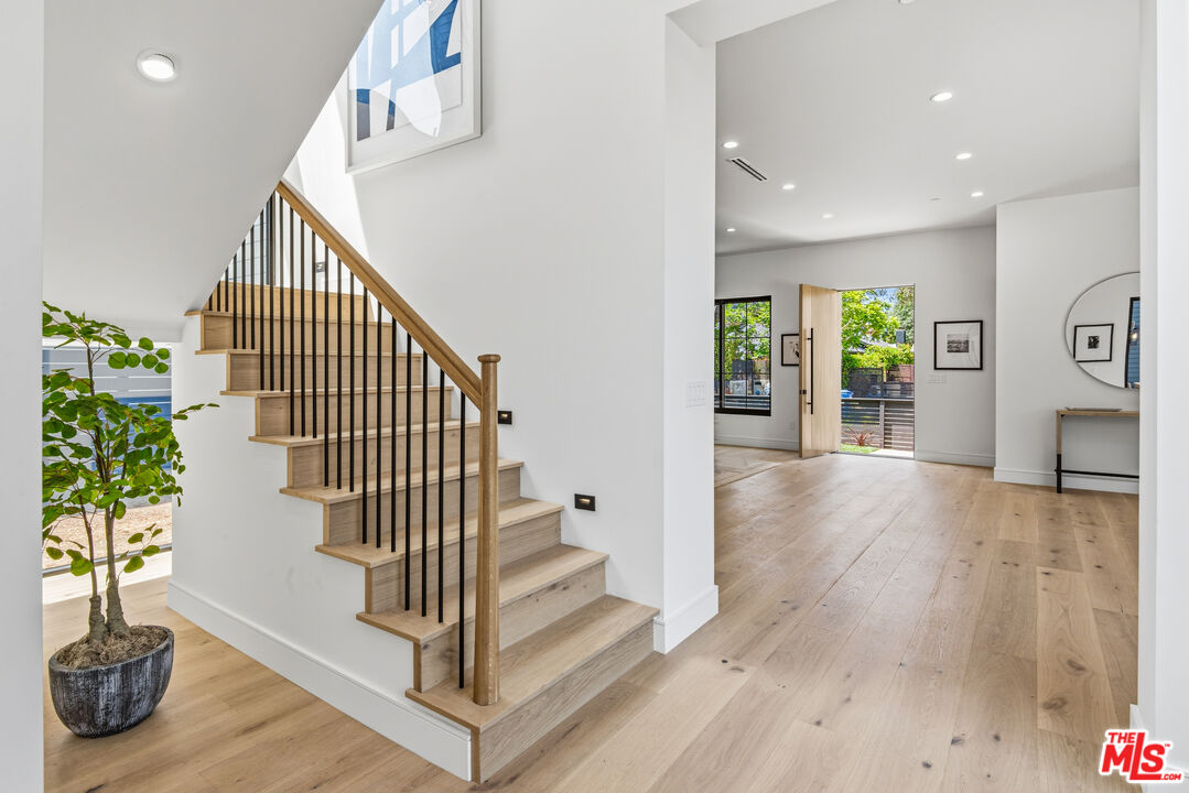 Modern entry with an oak staircase, black balusters, and wide-plank flooring.