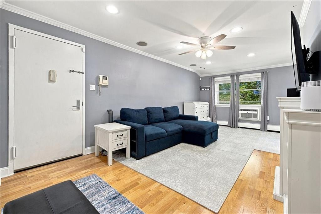 Living room with a navy sectional, hardwood floors, and windows overlooking greenery.