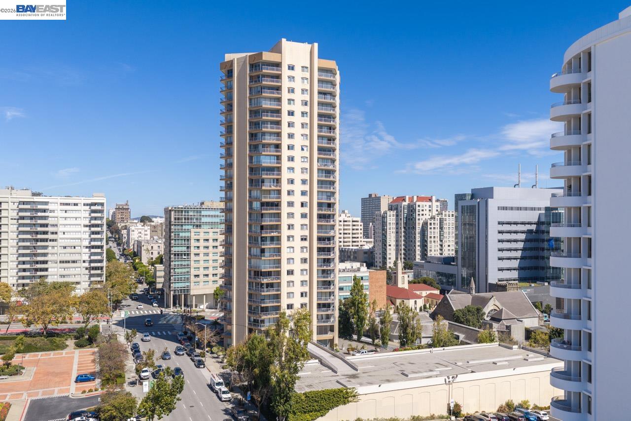 Residential tower with balconies rises above surrounding San Francisco streets and buildings.