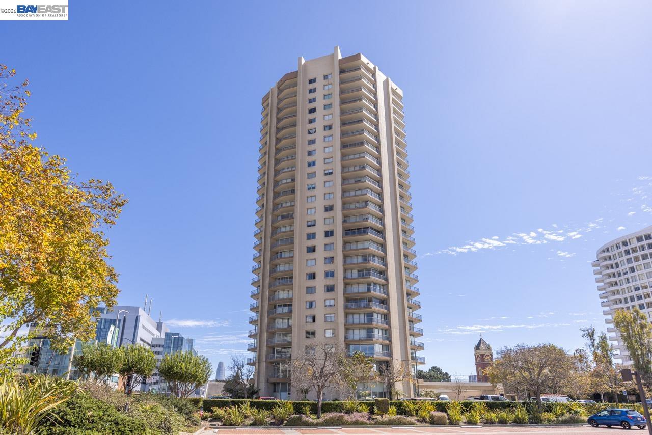 High-rise condominium tower with stacked balconies above landscaped grounds.