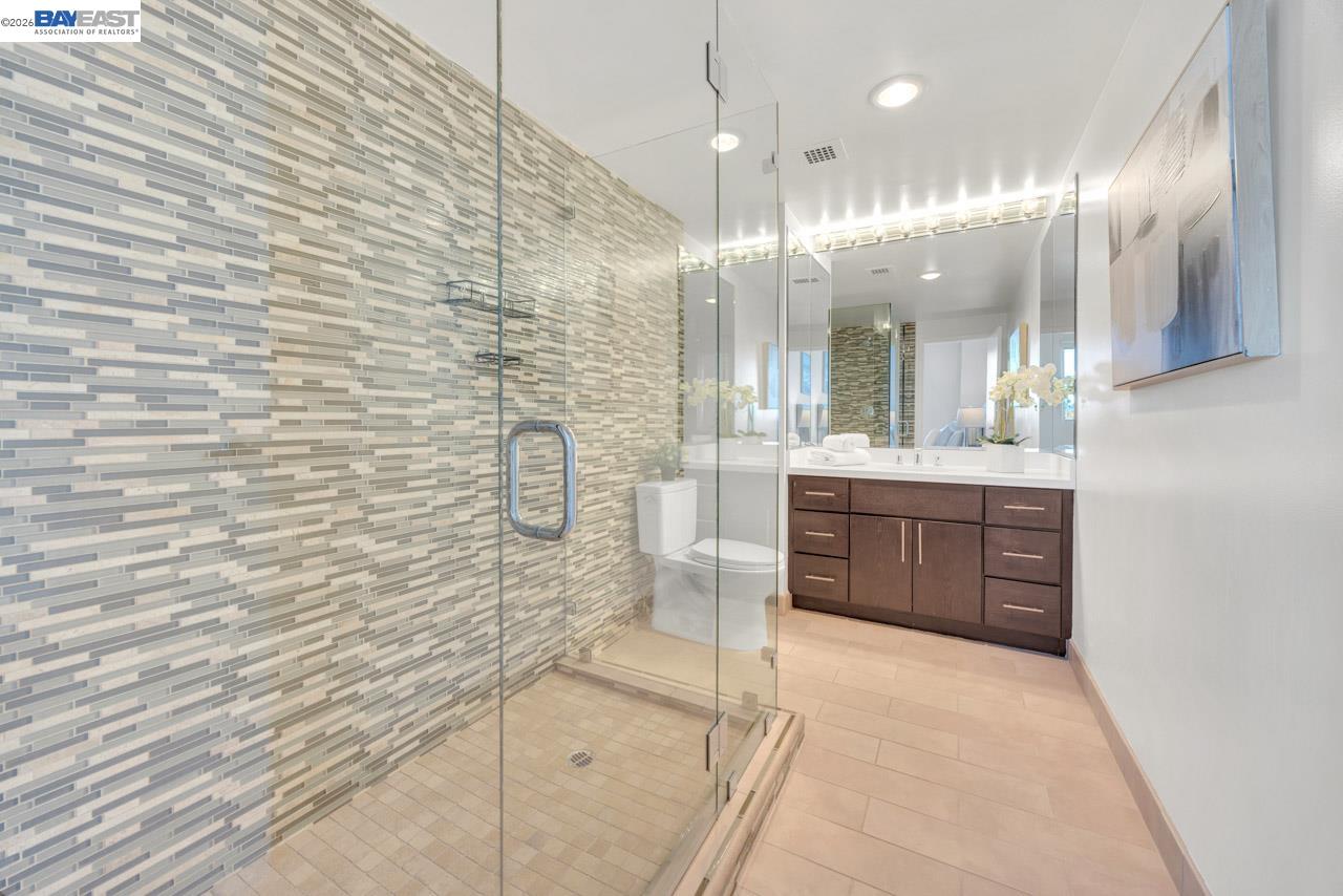 Modern bathroom with a glass shower, mosaic tile accent wall, and dark wood vanity.