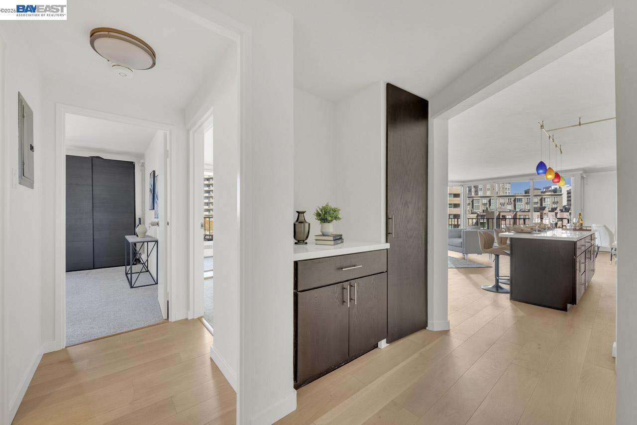 Condominium entry hall opening to a modern kitchen with a dark island and colorful pendant lights.