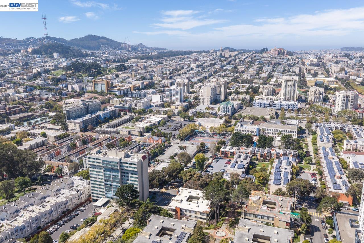 Aerial panorama of San Francisco neighborhoods, with tree-lined streets and hills in the distance.