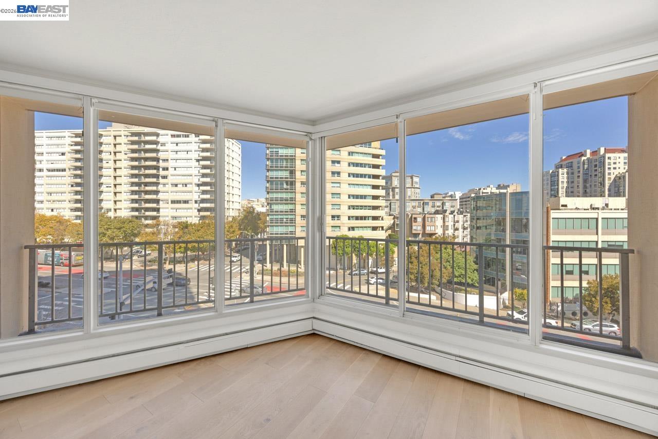 Empty condominium room with corner windows overlooking San Francisco buildings and streets.