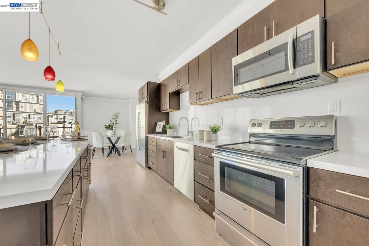 Kitchen with stainless steel appliances, dark wood cabinets, and a dining area by large windows.