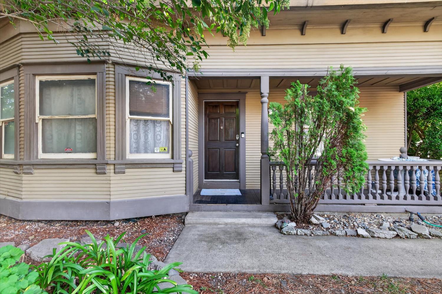 Home front with a covered porch, dark paneled entry door, bay windows, and landscaped walkway.