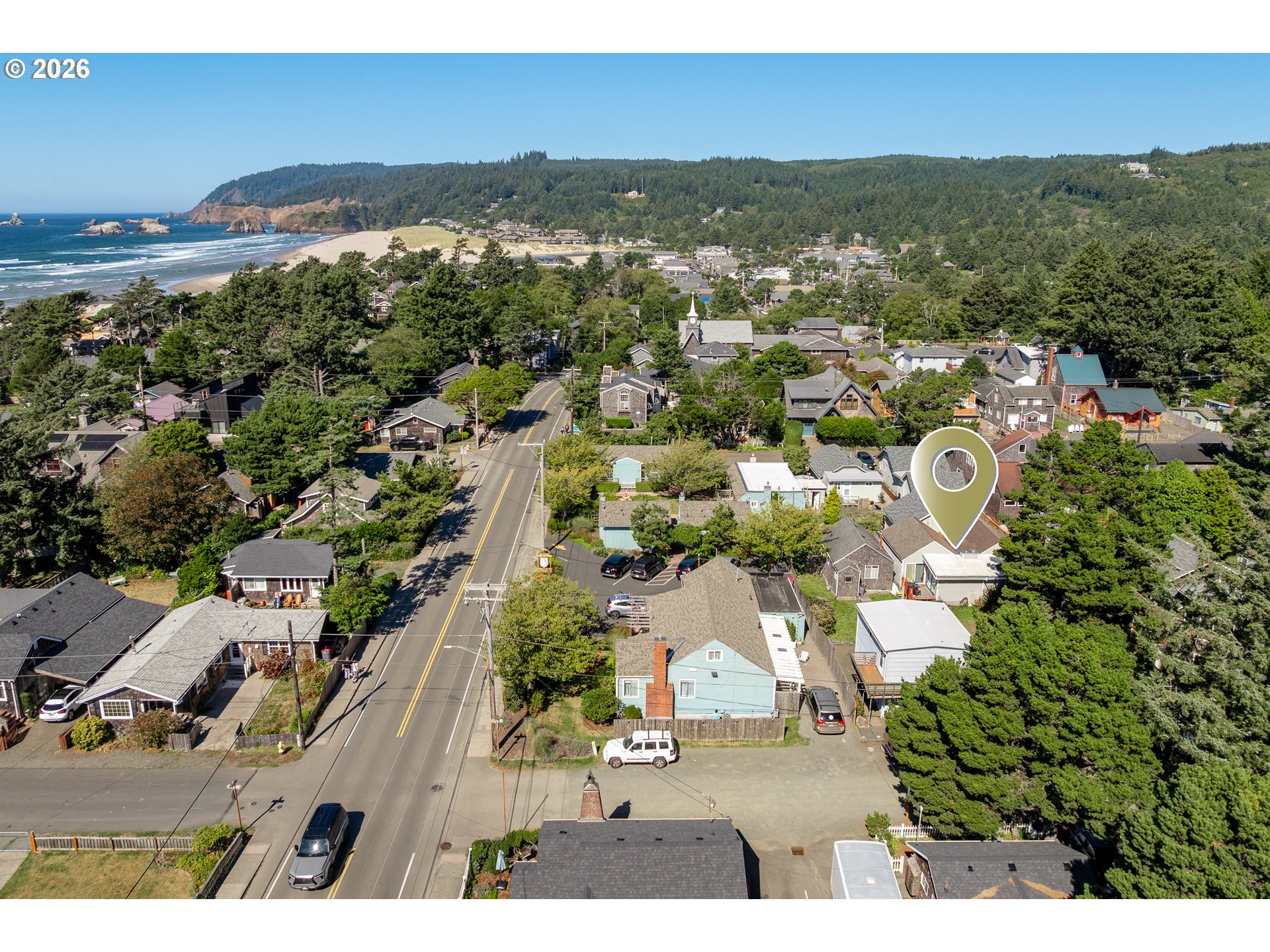 Aerial view of the marked property in a coastal neighborhood, with the beach and ocean beyond.