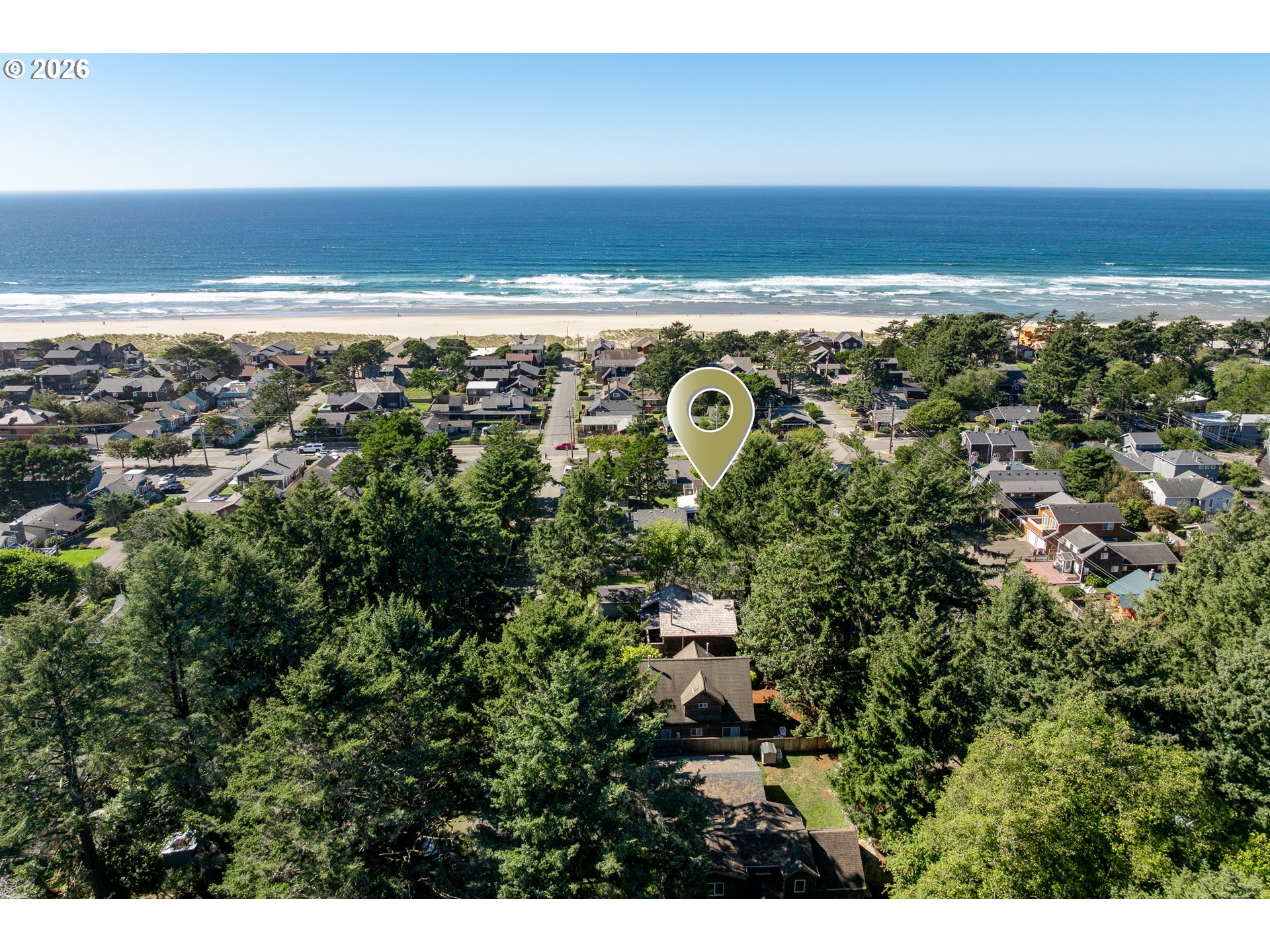 Aerial view of a Cannon Beach neighborhood, with a location pin and ocean beyond.