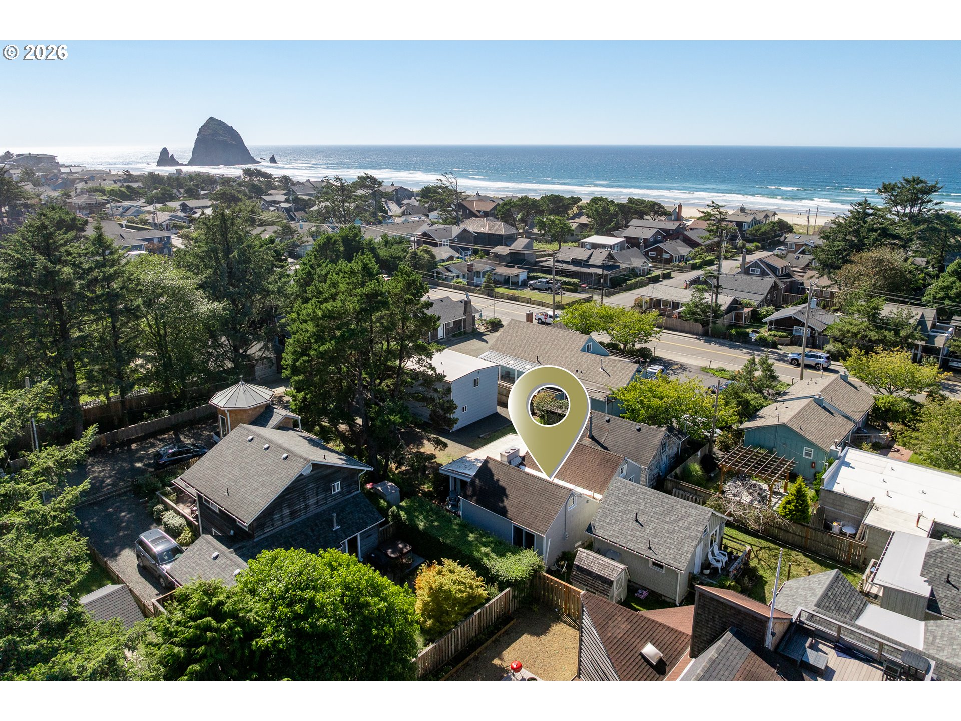 Aerial view of a Cannon Beach home, with the ocean and Haystack Rock beyond the neighborhood.