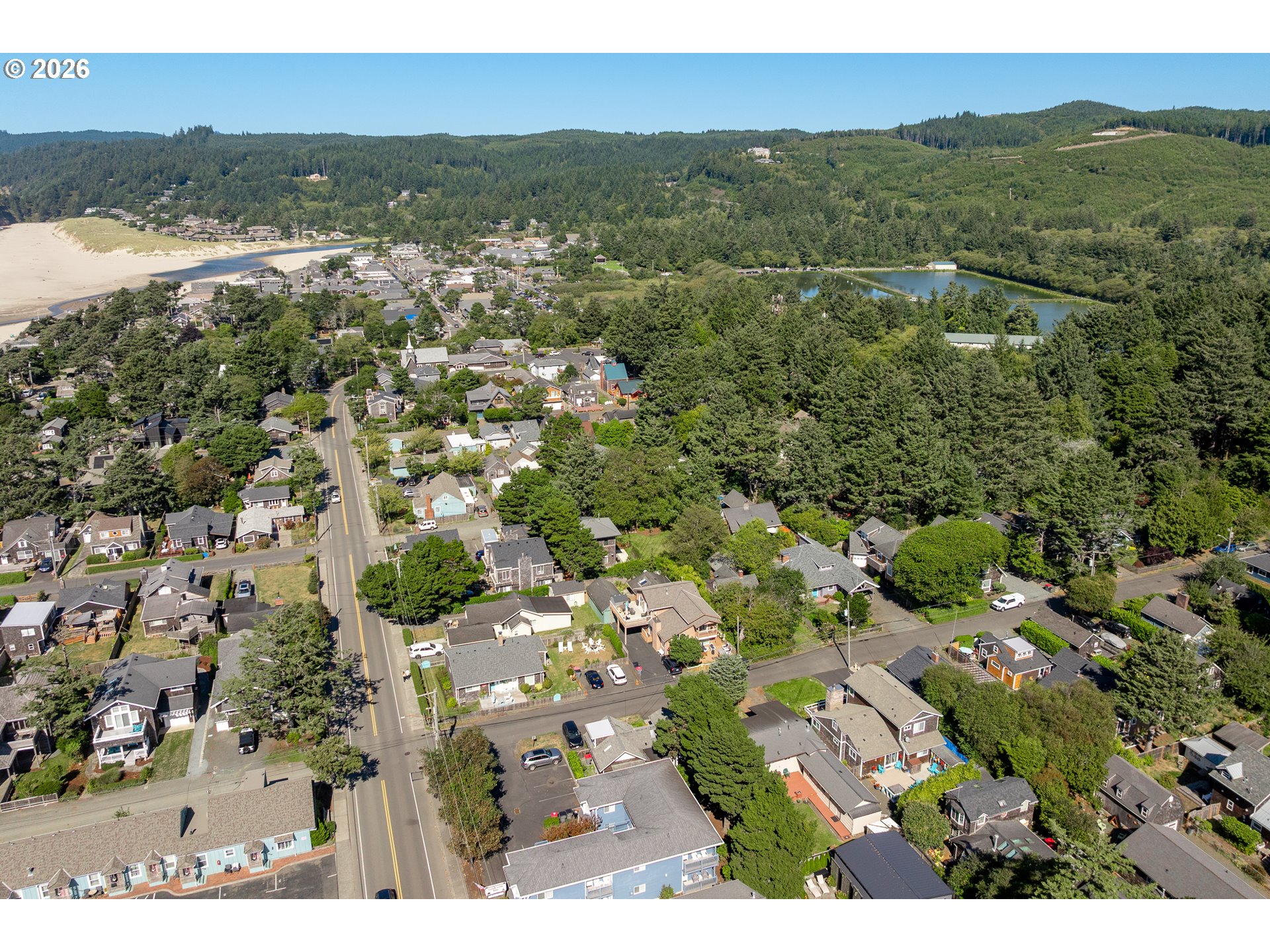 Aerial view of Cannon Beach homes, with the sandy beach and wooded hills nearby.
