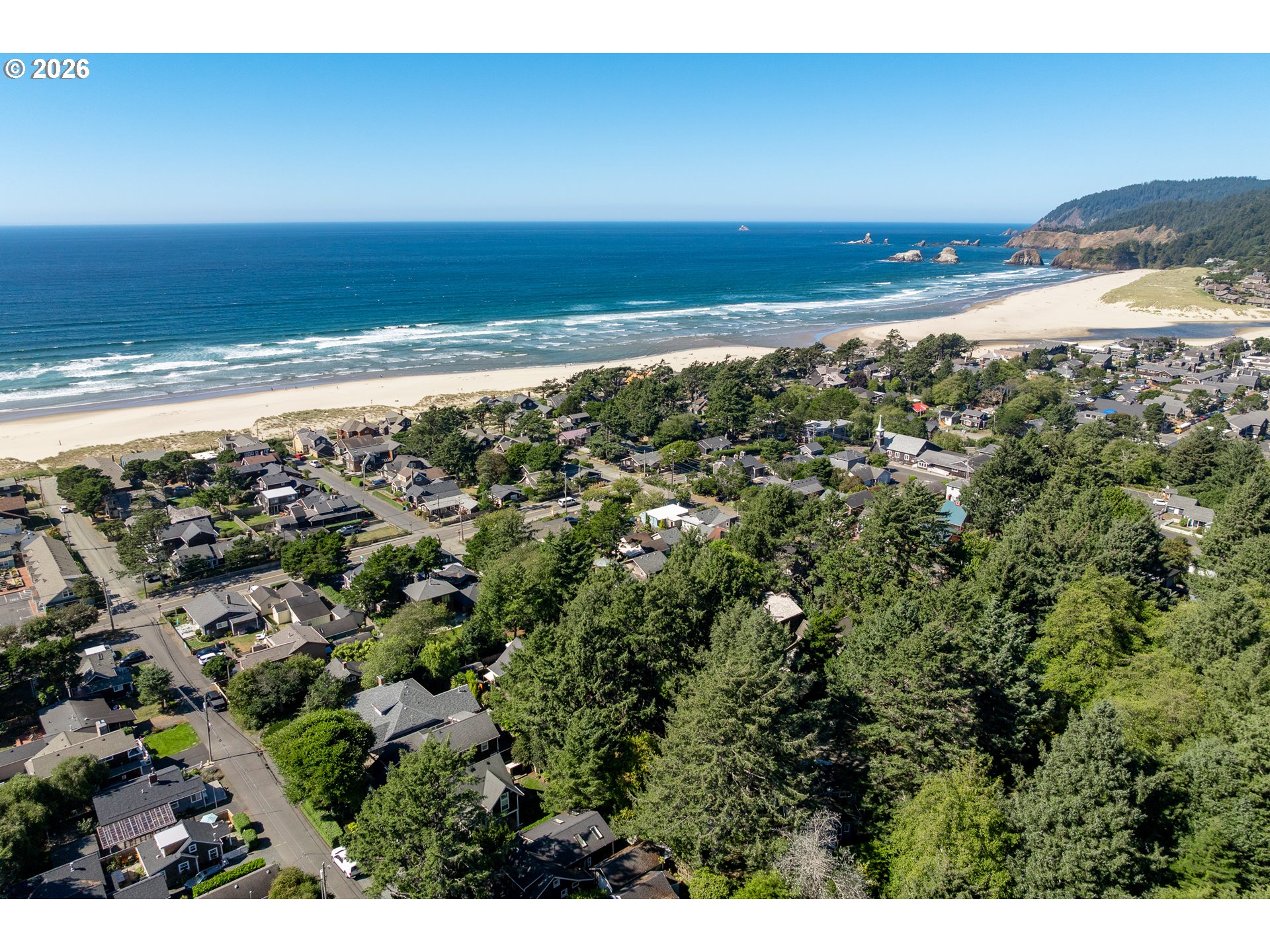 Aerial view of a coastal neighborhood beside a broad sandy beach and blue ocean.