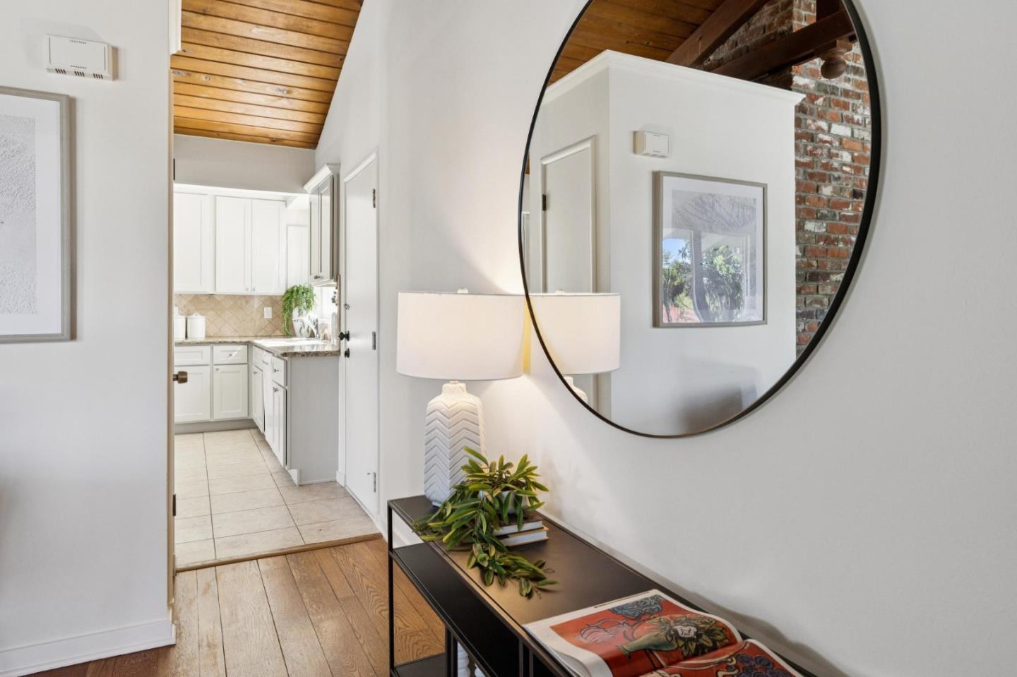 Entry hallway with a round mirror and console table, opening into a bright white kitchen.