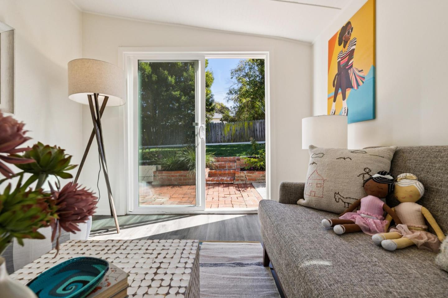 Living room with a gray sofa and sliding doors opening to a brick patio.
