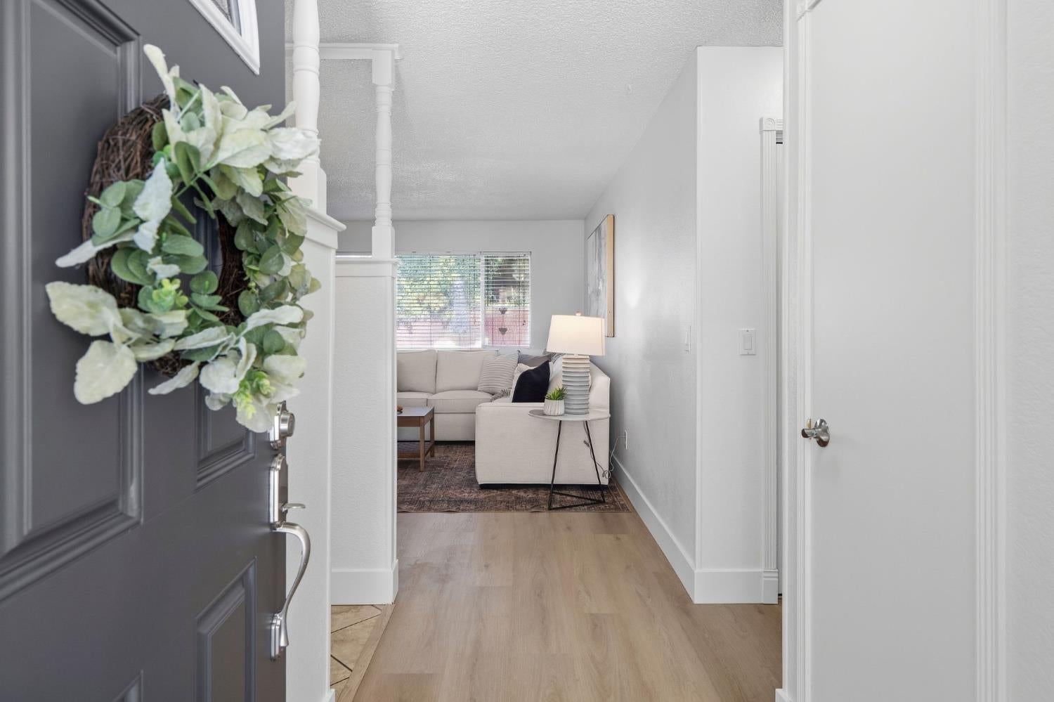 Entry hallway with a wreath-covered front door and a furnished living room beyond.