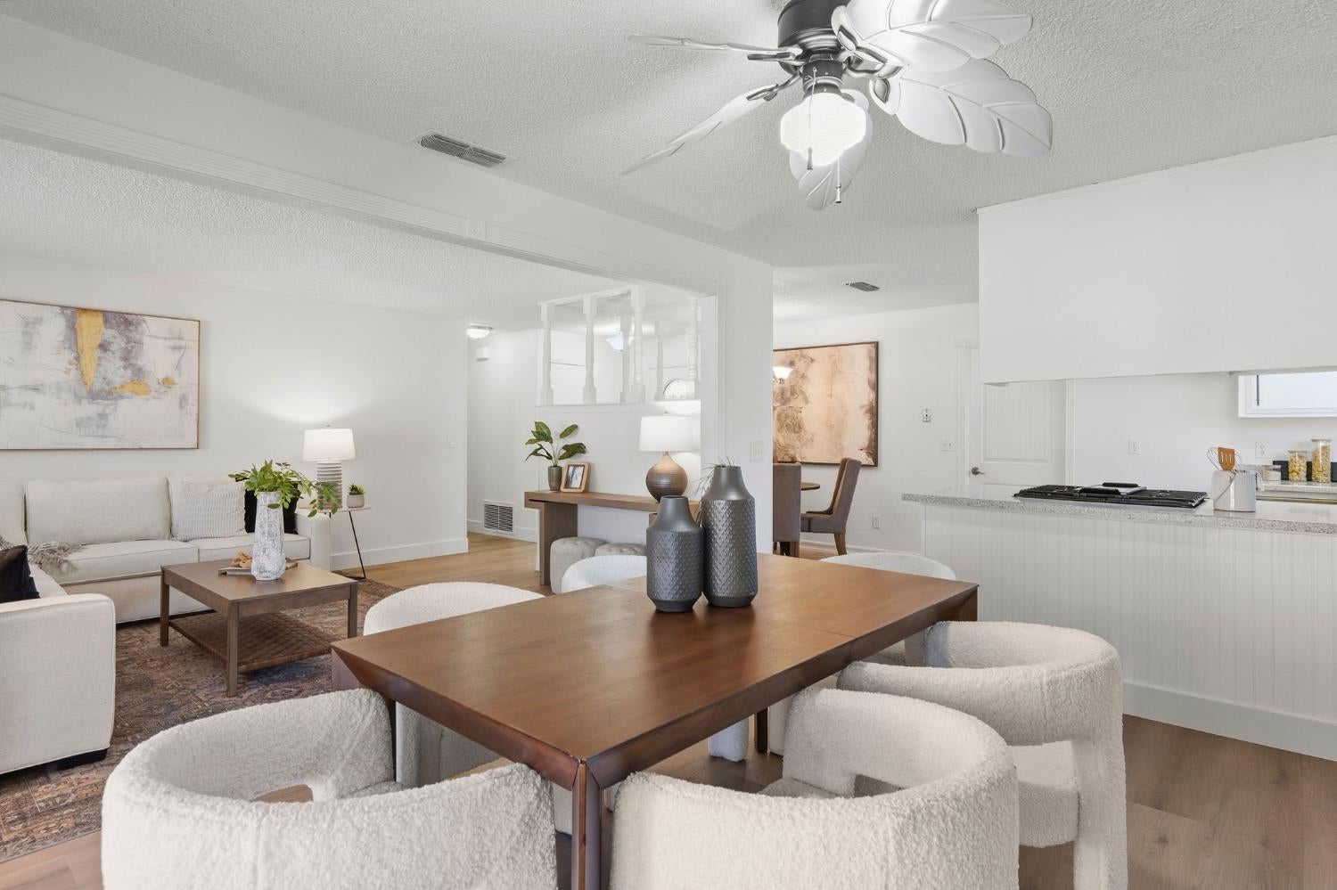 Open-plan living and dining area with a wood table, upholstered chairs, and kitchen island.