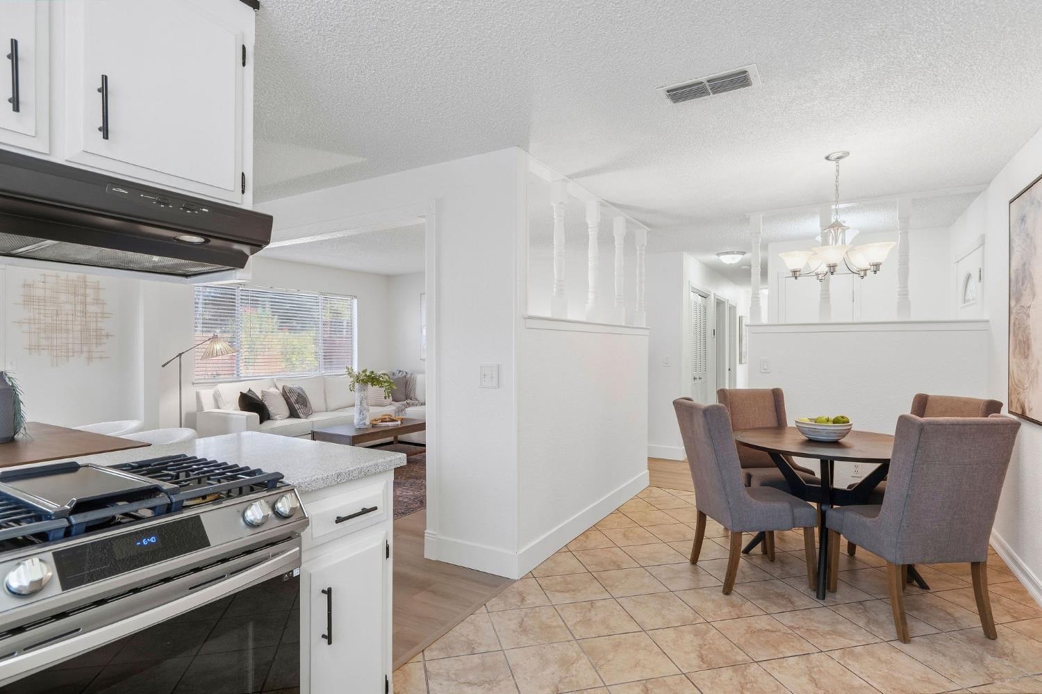 Open kitchen and dining area with a stainless-steel range, white cabinets, and adjoining living room.
