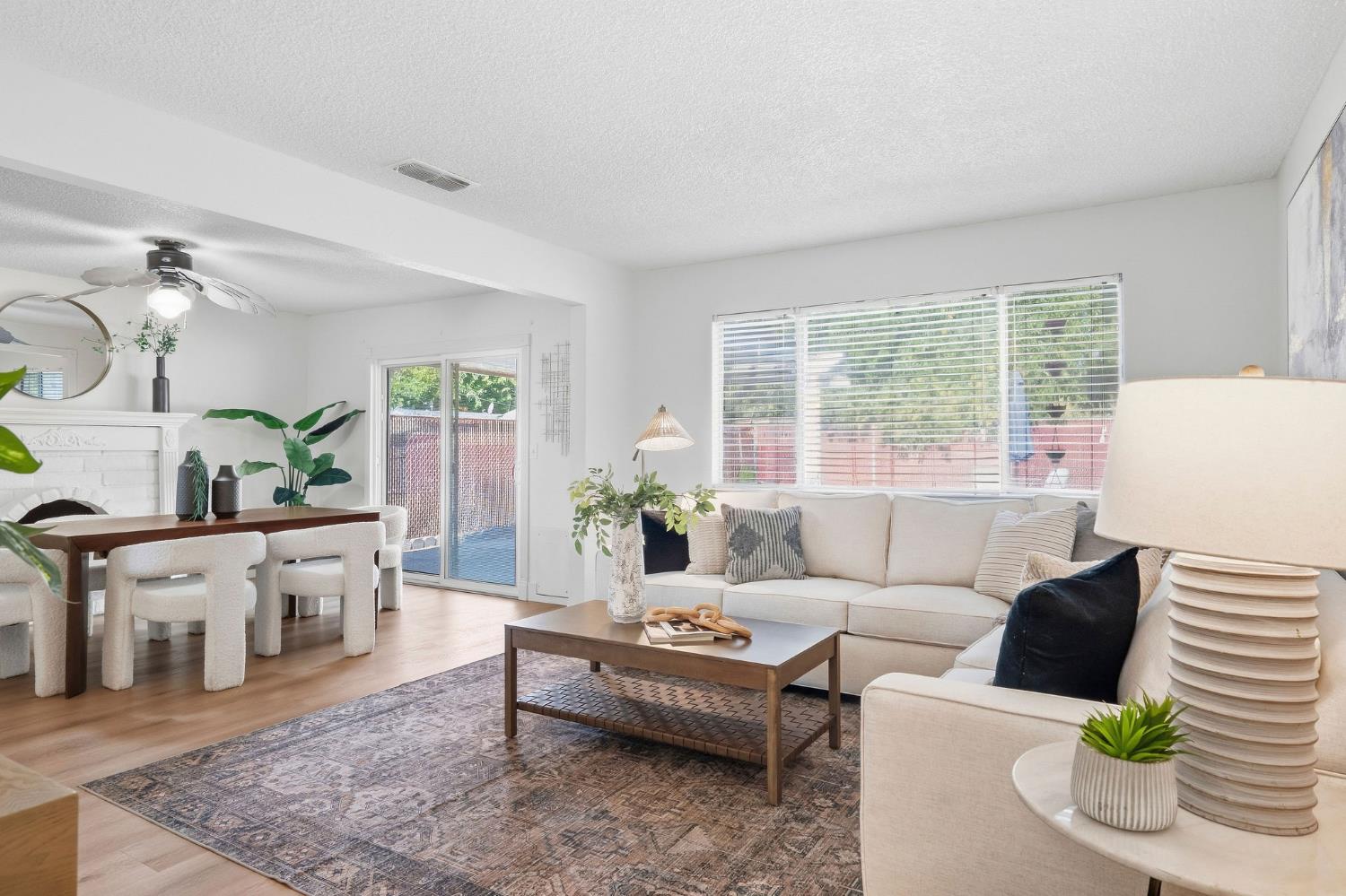 Living room with a cream sectional, patterned rug, white fireplace, and adjoining dining area.