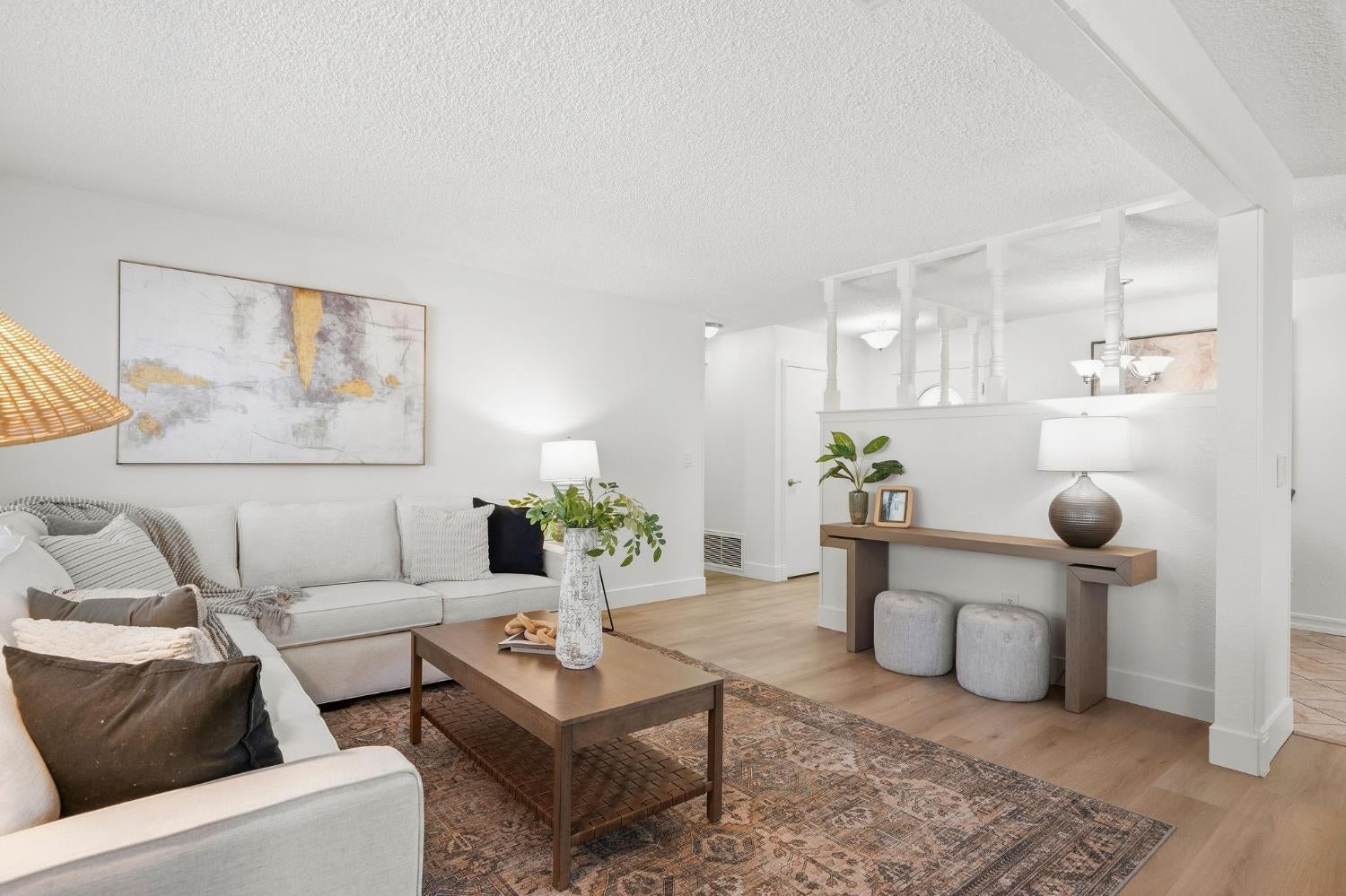 Staged living room with a light sectional, wooden coffee table, and patterned rug.