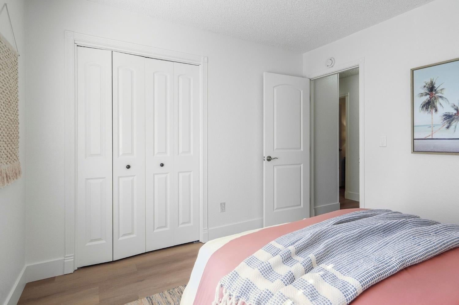 Bedroom with pink bedding, a blue-and-white quilt, and white paneled closet doors.