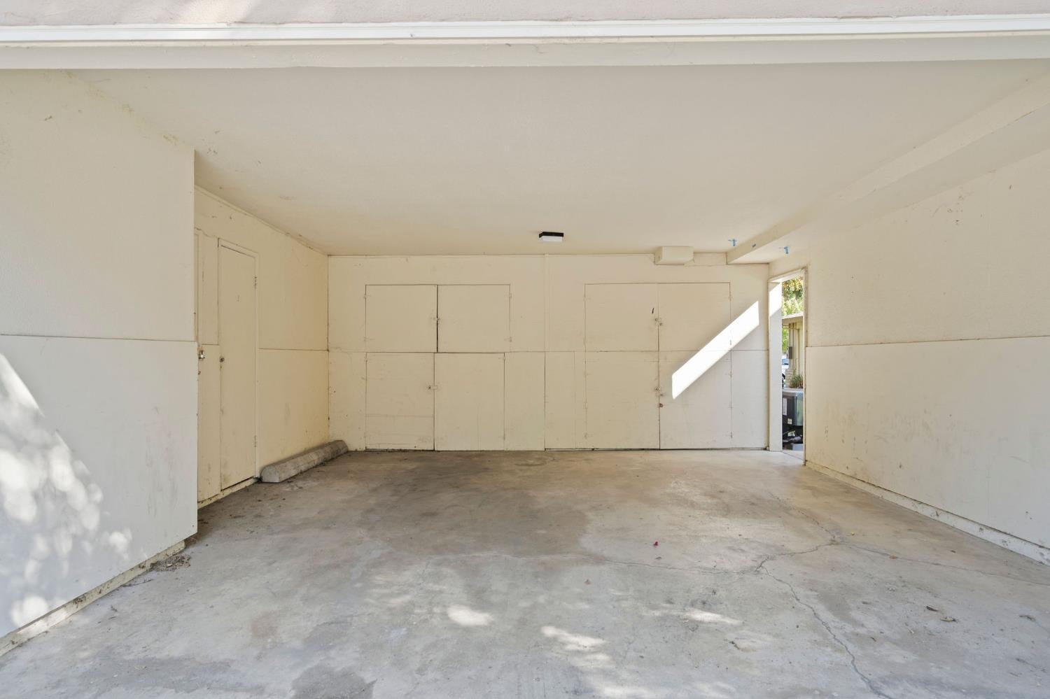 Empty garage with built-in storage cabinets and a cracked concrete floor.