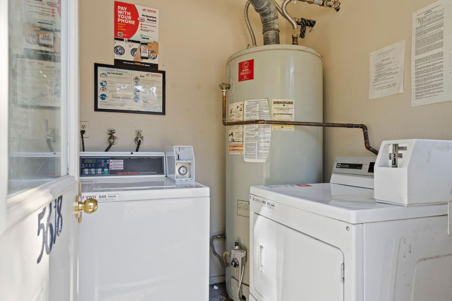 Laundry room with commercial washers, a dryer, and a large water heater.
