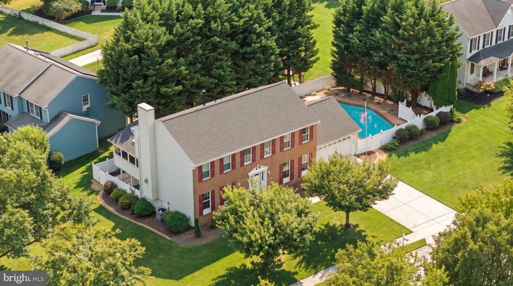 Aerial view of a two-story brick home with a backyard swimming pool and broad lawn.