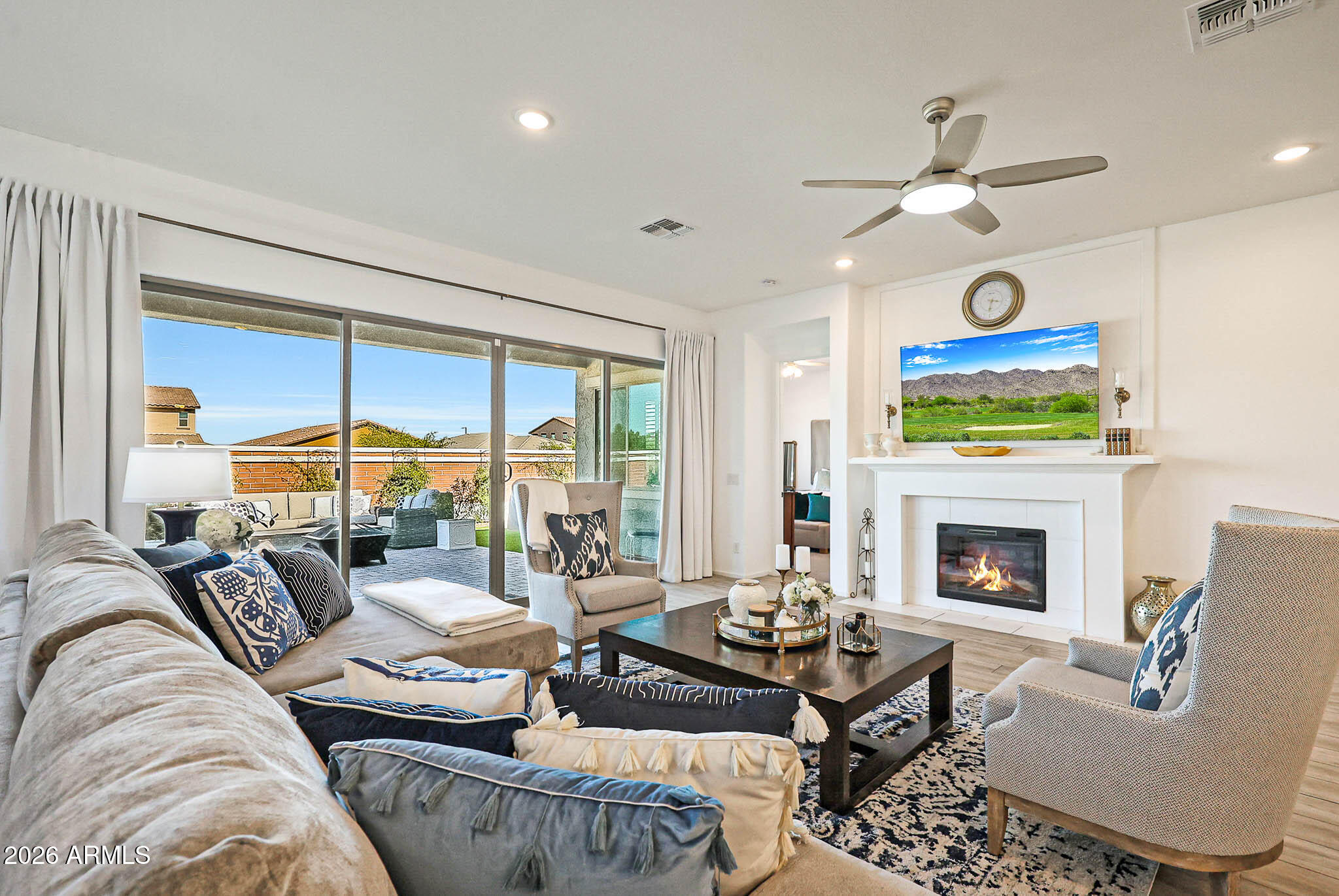 Furnished living room with a fireplace, ceiling fan, and sliding doors to a patio.