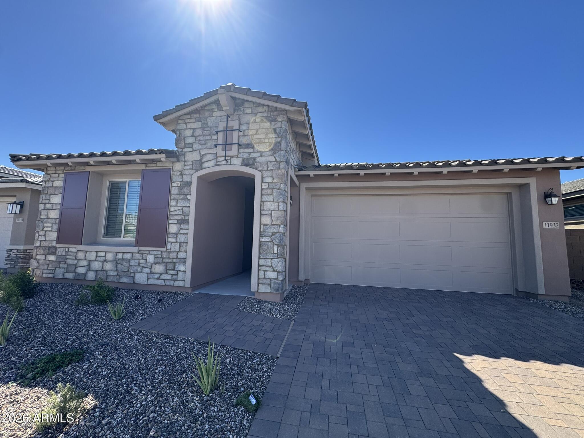 Home with a stone facade, arched entry, and attached two-car garage.