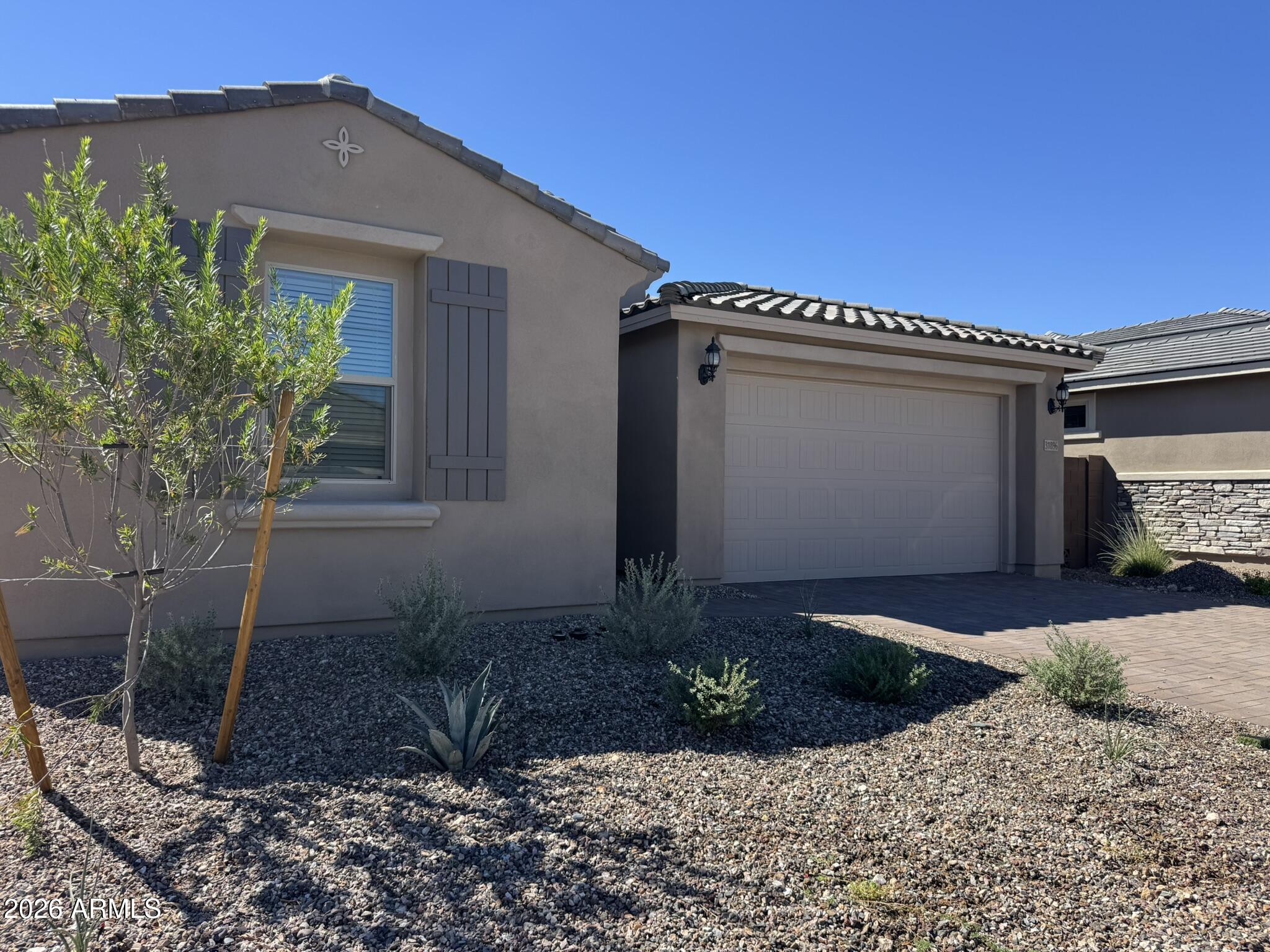 Stucco home with an attached double garage and gravel desert landscaping.