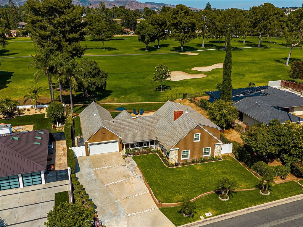 Single-story home beside a golf course, with a broad driveway and landscaped lawn.
