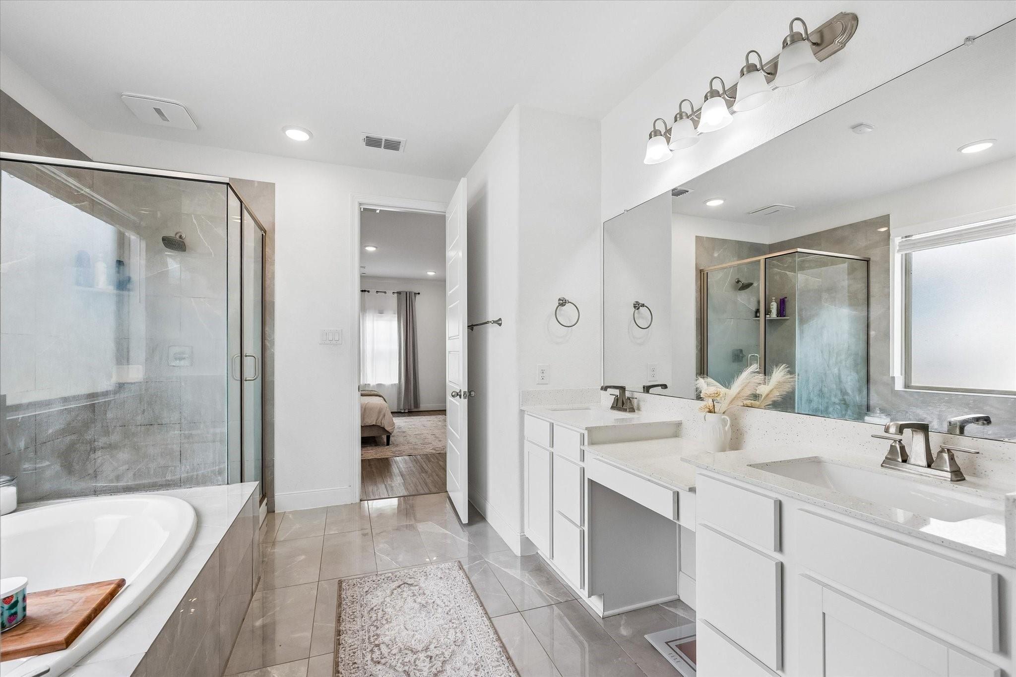 Primary bathroom with a double vanity, glass shower, and soaking tub.