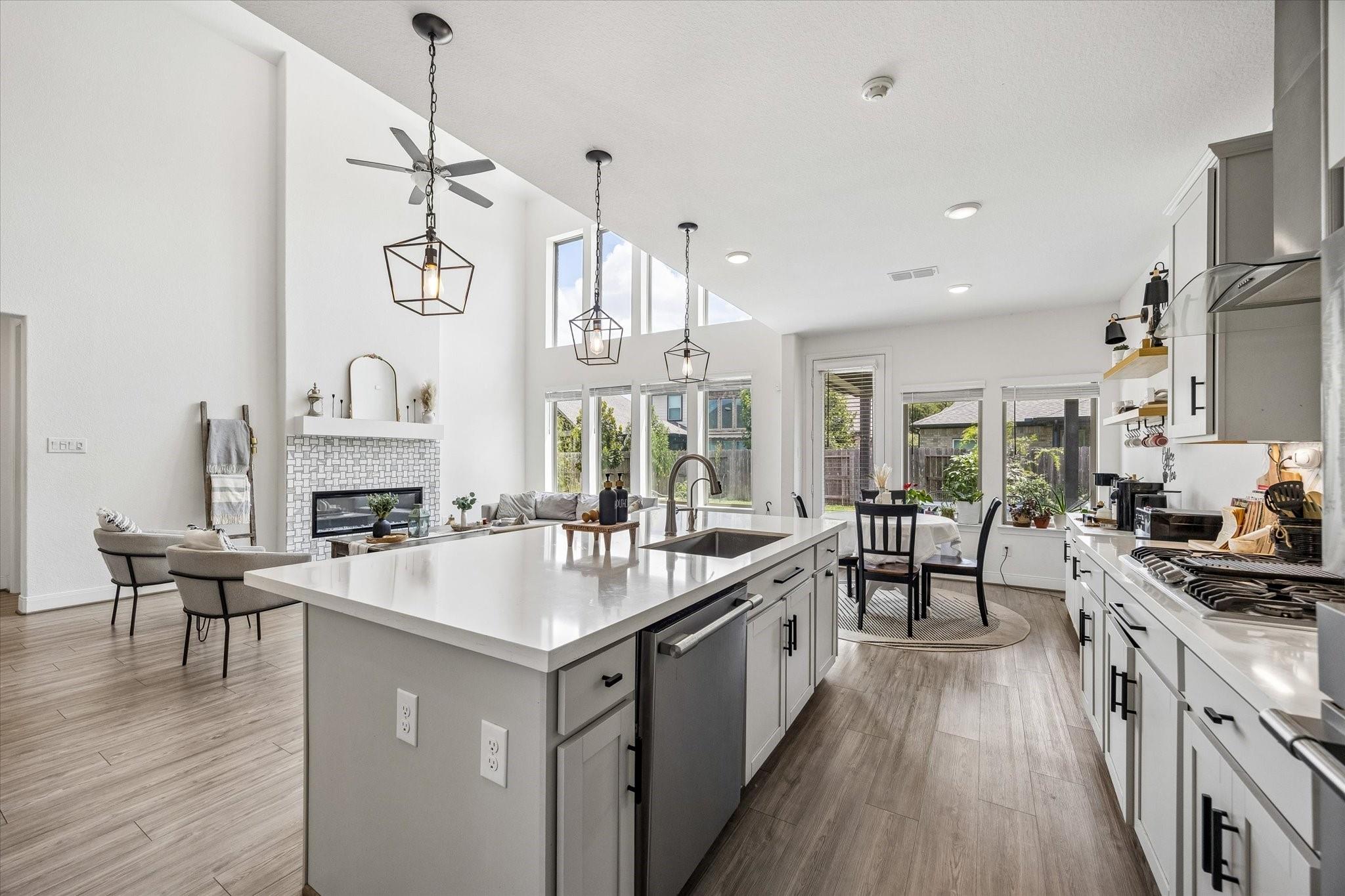 Open-plan kitchen with a large white island, pendant lights, and adjoining dining and living areas.