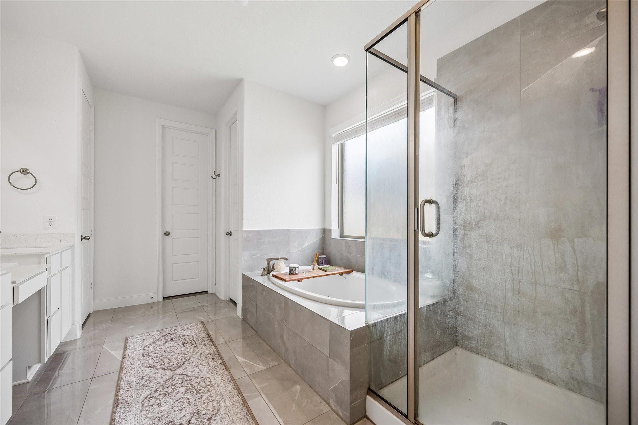 Modern bathroom with a glass shower, built-in soaking tub, and gray tile.