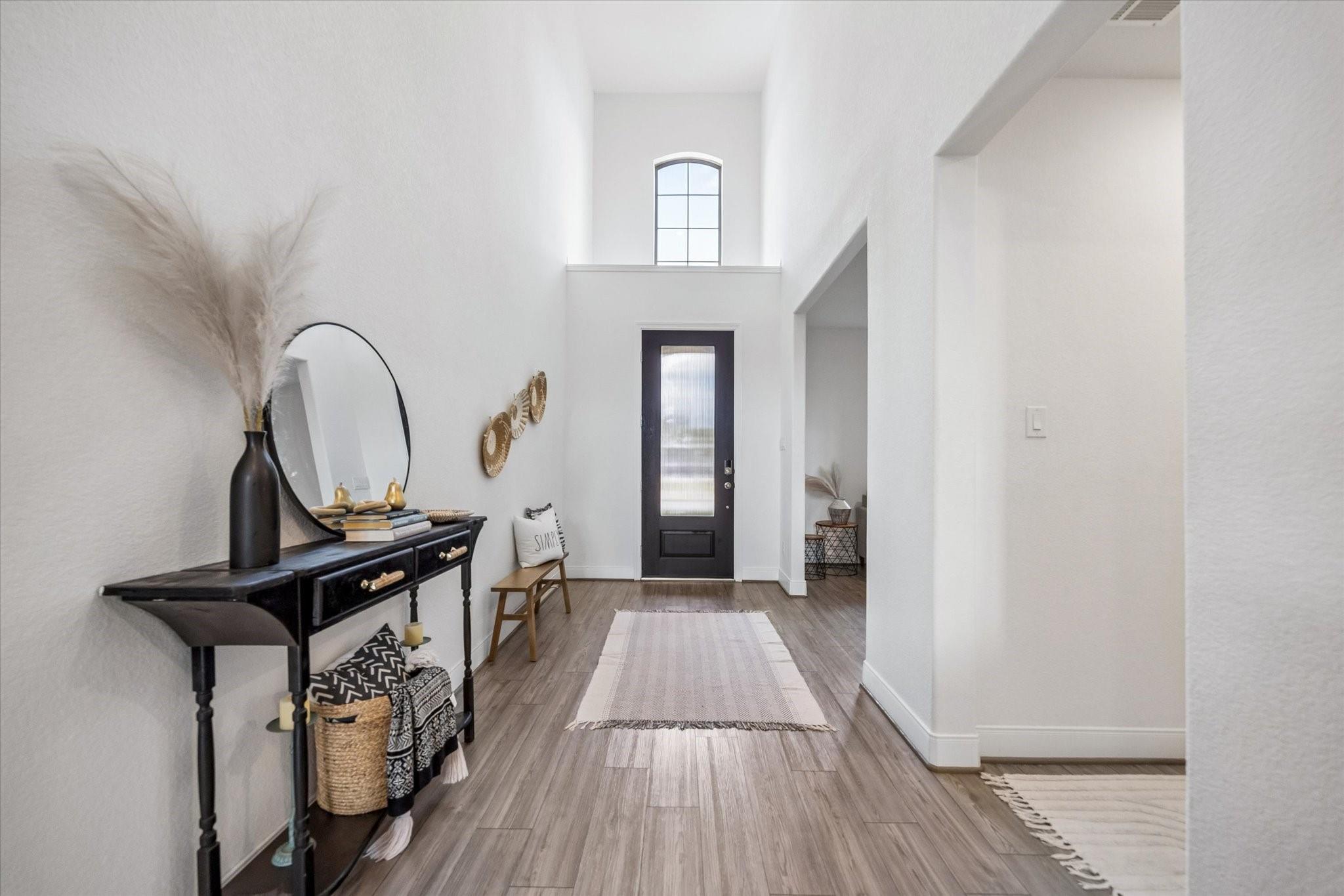 Staged entryway with a tall ceiling, arched window above the front door, and black console table.