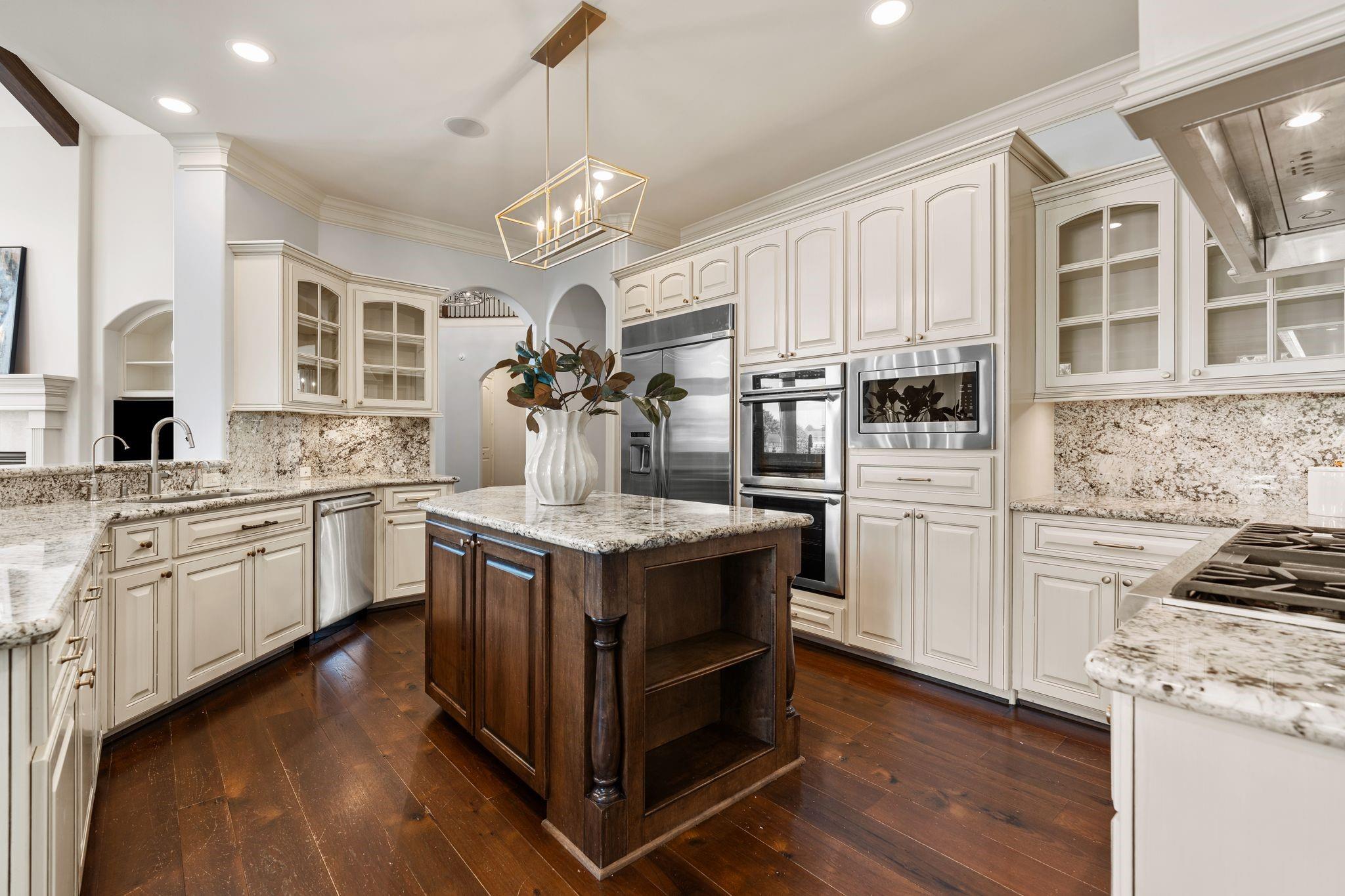 Kitchen with cream cabinetry, stainless steel appliances, and a dark wood island with granite countertop.