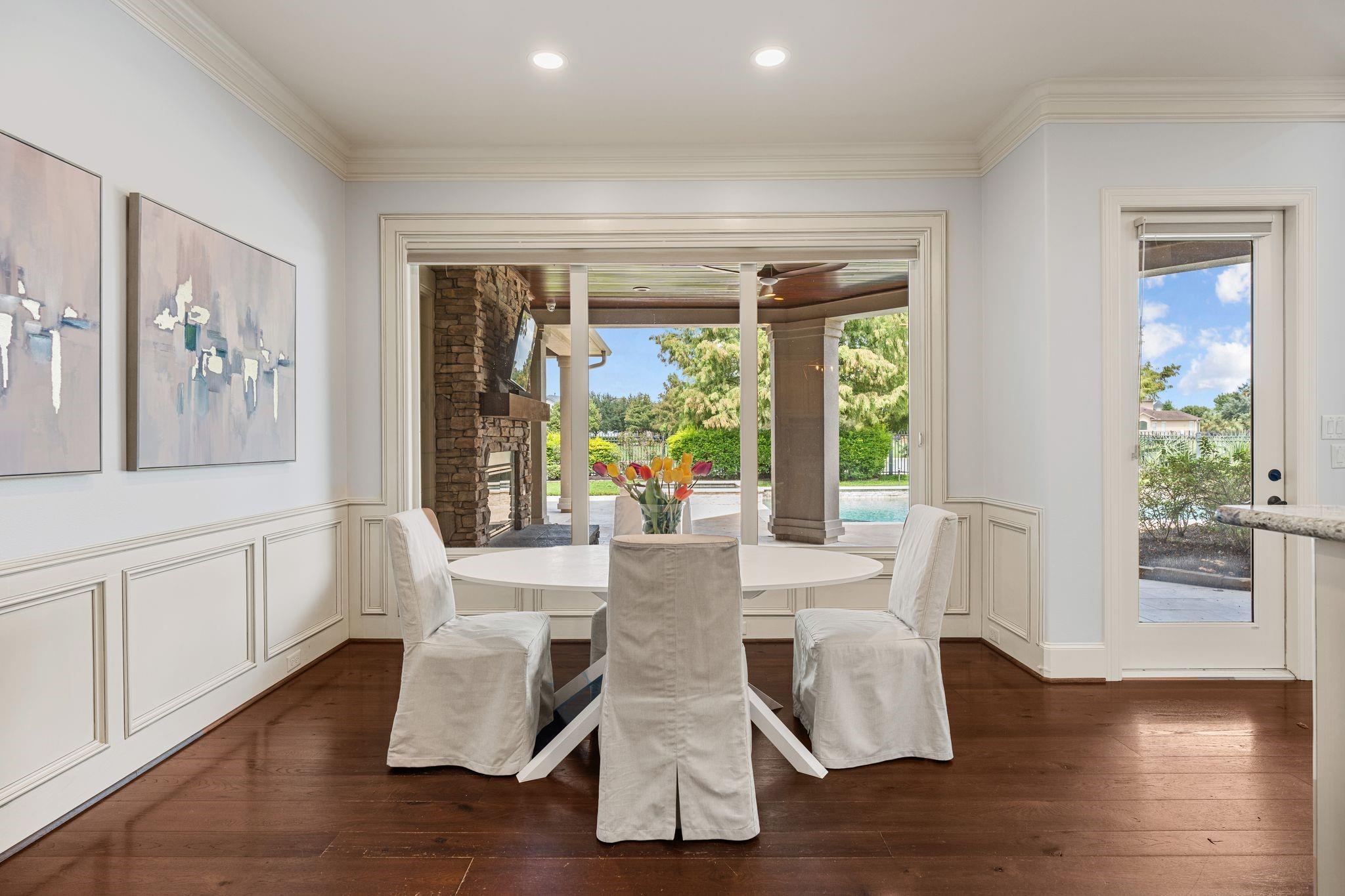 Dining room with a round table and views through large windows to a covered patio and pool.