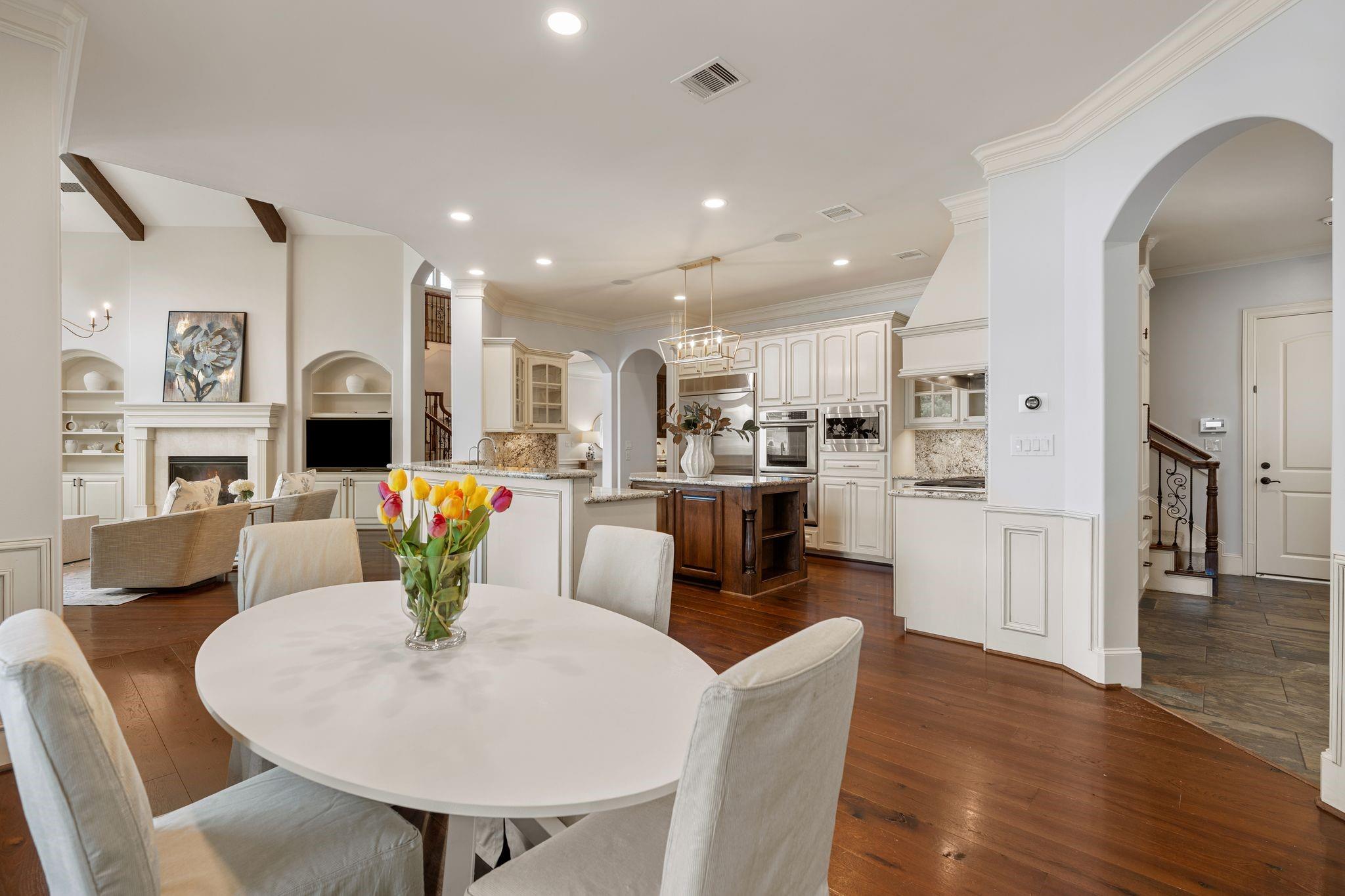 Open-plan kitchen and dining area with white cabinetry, dark wood island, and tulips on the table.