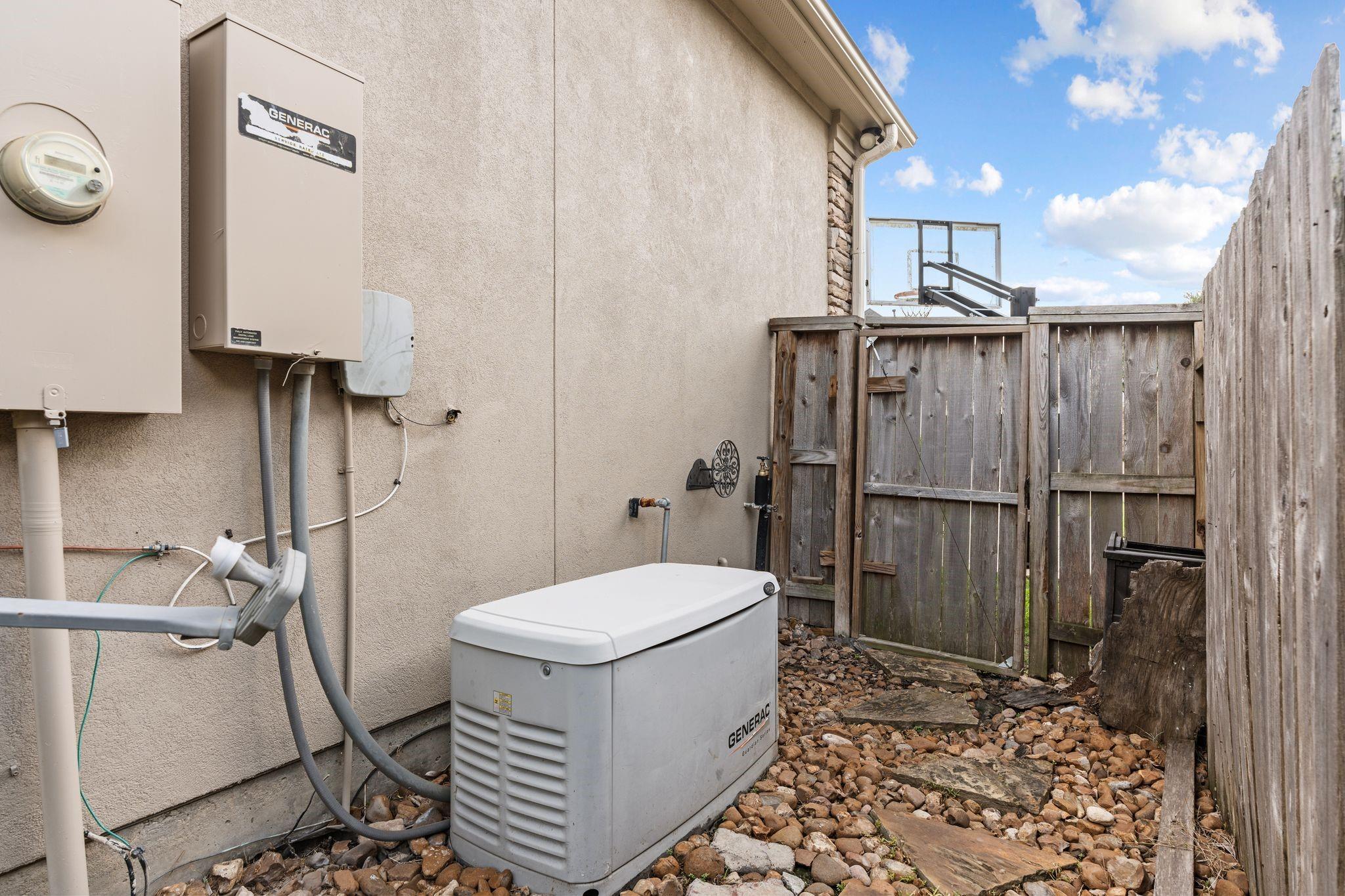Whole-house Generac generator beside the home's fenced side yard.