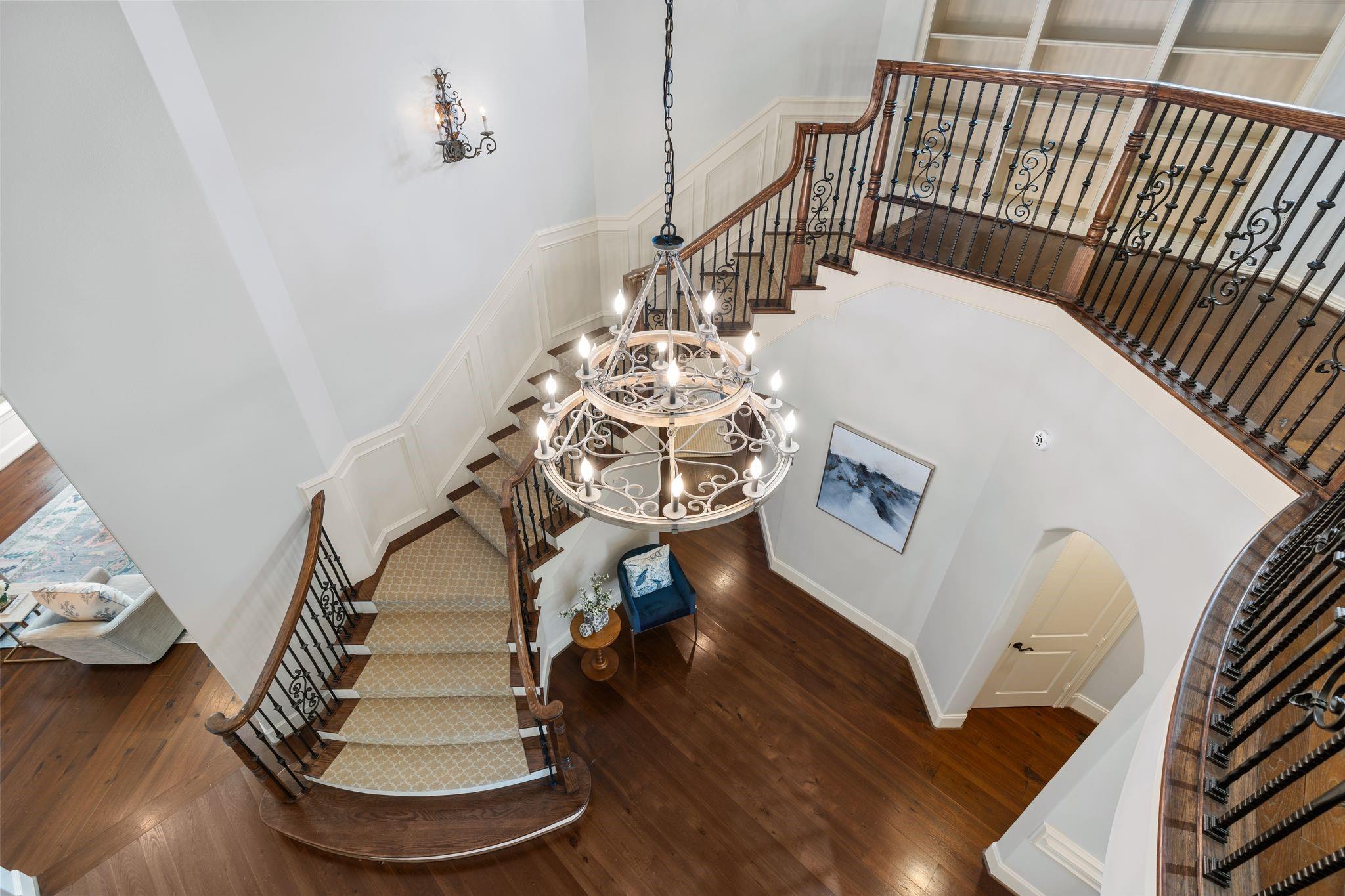 Two-story foyer with a sweeping curved staircase, ornate iron railings, and a large chandelier.