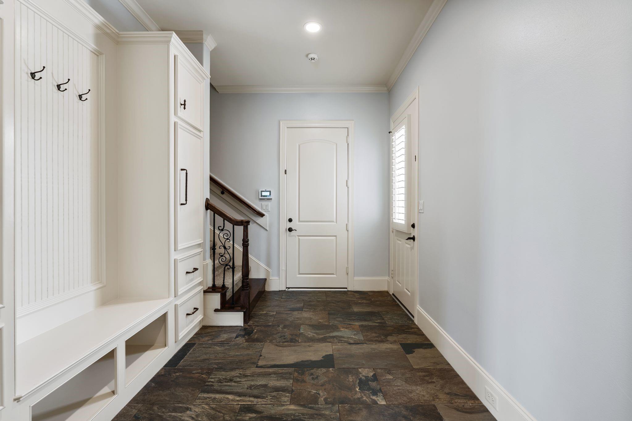 Entry hall with slate tile, built-in bench and coat hooks, and a staircase beside the front door.