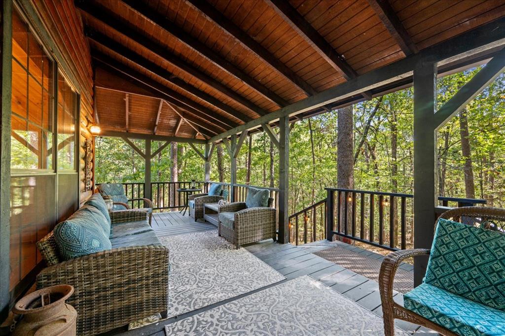 Covered deck with wicker seating and a wooded view.