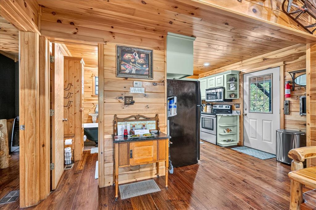 Wood-paneled cabin kitchen with a black refrigerator and white door opening outside.