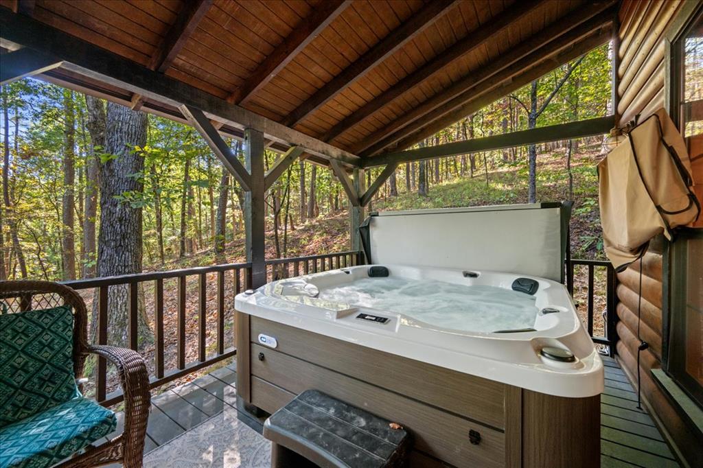 Hot tub on a covered wooden deck overlooking a wooded hillside.